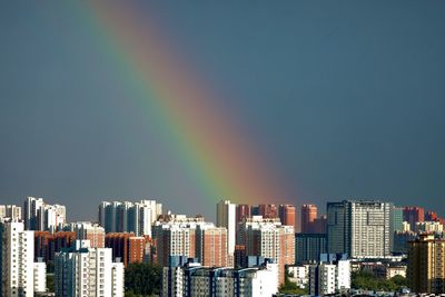 Rainbow over city buildings against sky