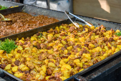 Chicken and potatoes in large tray on street food stall in budapest, hungary