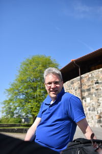 Portrait of smiling man against blue sky during sunny day