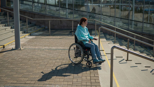 Disabled woman sitting on wheelchair near steps