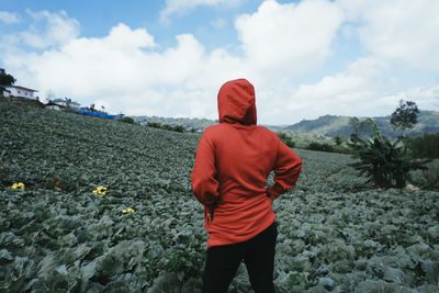 Rear view of woman standing amidst plants against sky