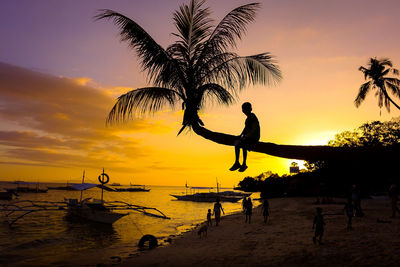 Silhouette people on beach against sky during sunset