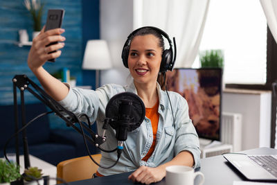 Portrait of young woman using mobile phone while sitting at home