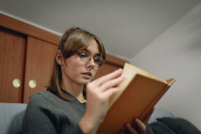 Portrait of young woman reading book at home