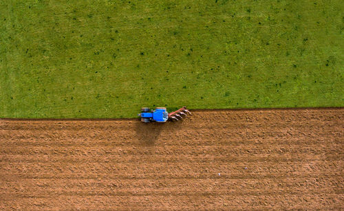 Aerial high angle view of tractor ploughing field