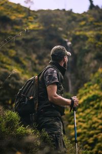 Side view of man with backpack standing in forest