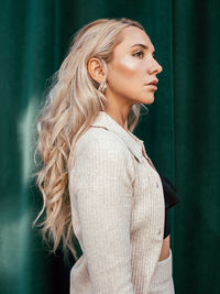 Portrait of young woman standing against wall