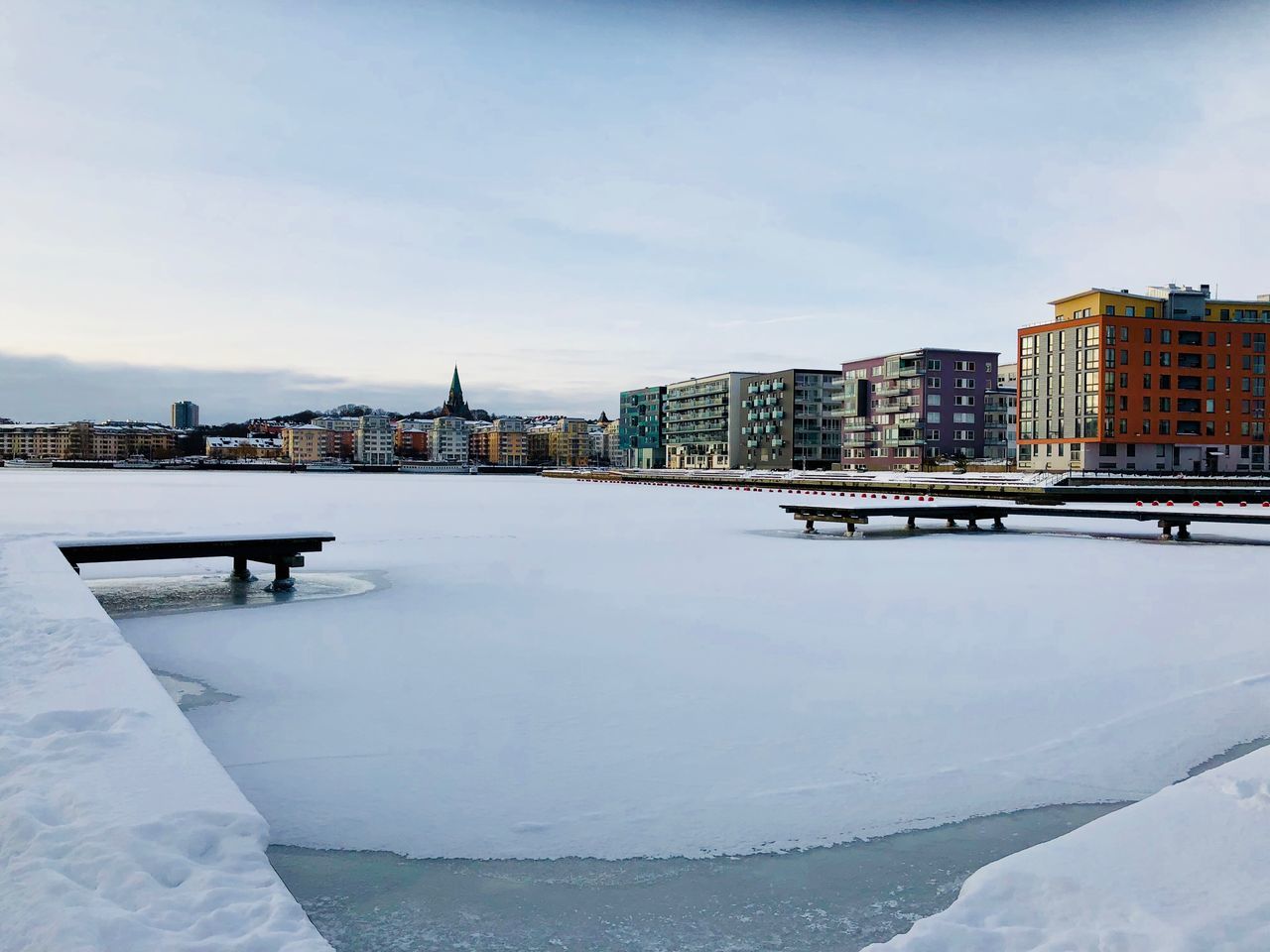 architecture, built structure, building exterior, city, winter, sky, skyscraper, snow, cityscape, cold temperature, outdoors, water, river, travel destinations, day, urban skyline, modern, no people, nature