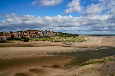 Scenic view of beach by buildings against sky