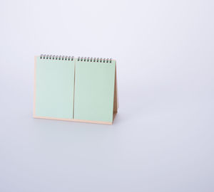 High angle view of blank green desk calendar against white background