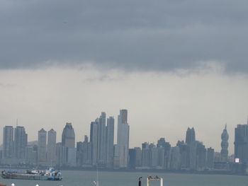 Sea and modern buildings in city against sky