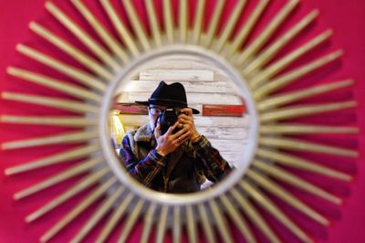 Reflection of man photographing in car mirror