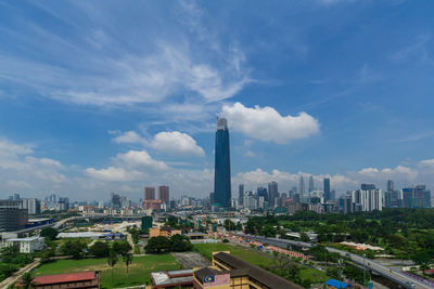 Aerial view of buildings in city against cloudy sky