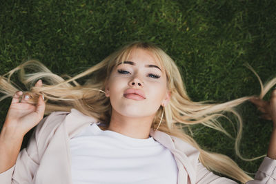 High angle portrait of beautiful young woman lying on grass