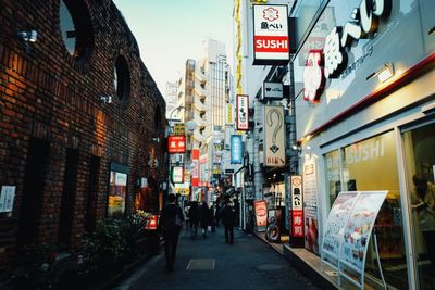 People walking on street amidst buildings in city