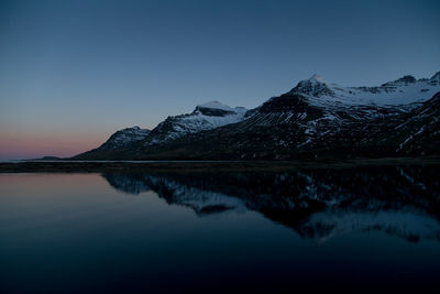 Scenic view of lake and snowcapped mountains against sky during sunset