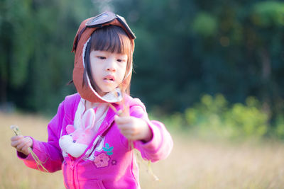 Girl holding flowers while standing on field