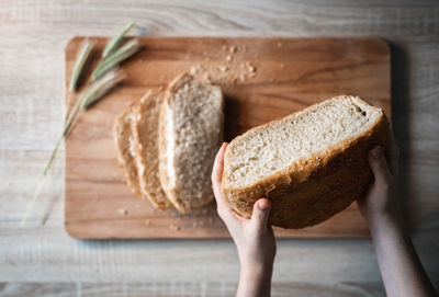 Close-up of hand holding bread on cutting board