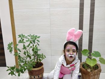 Portrait of cute girl standing by potted plants