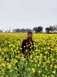 Portrait of woman with yellow flowers in field