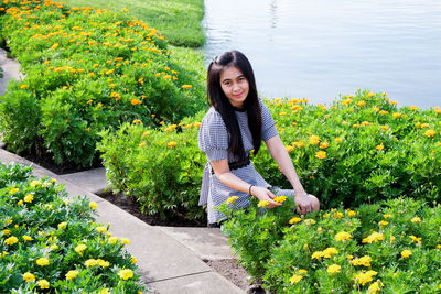 Portrait of smiling woman crouching amidst yellow flowers 