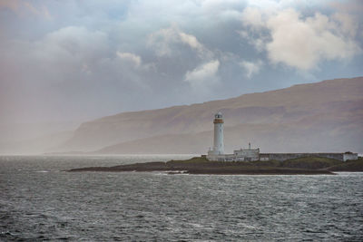 Lighthouse by sea against sky