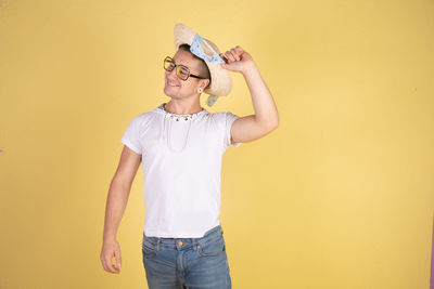 Young man standing against yellow wall