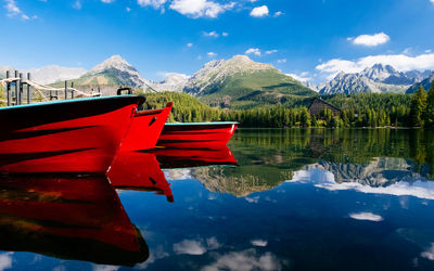 Red boat moored on lake against sky