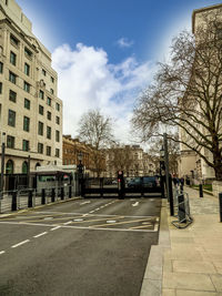 Road by buildings against sky in city