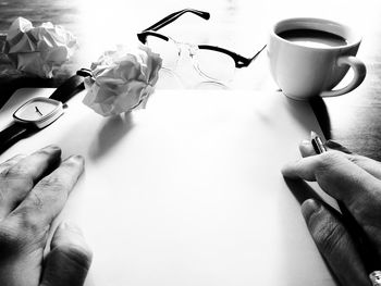 Close-up of hand holding coffee cup on table