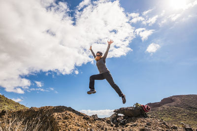 Low angle view of woman jumping on land against sky