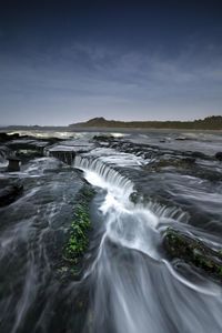 Scenic view of waterfall against sky