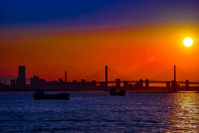 Silhouette of bridge over sea during sunset