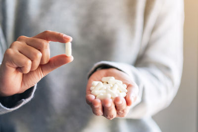 Midsection of woman holding capsules