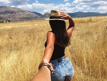 Woman holding hand of man while standing on agricultural field