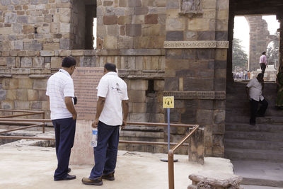 Rear view of man and daughter against building