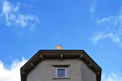 Low angle view of statue on roof against blue sky