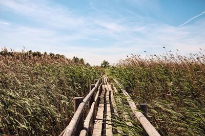 Railroad track on field against cloudy sky