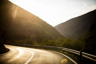 Empty road against mountains during sunrise