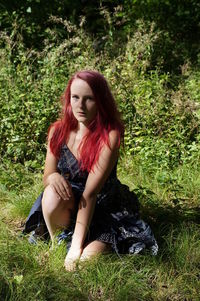 Portrait of redhead woman sitting on grassy field