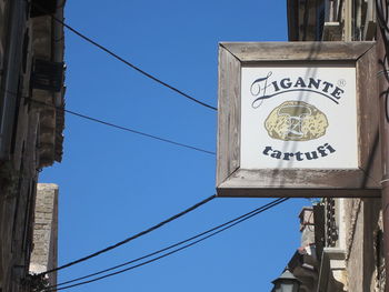 Low angle view of road sign against blue sky