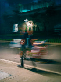 Blurred motion of man riding motorcycle on road at night