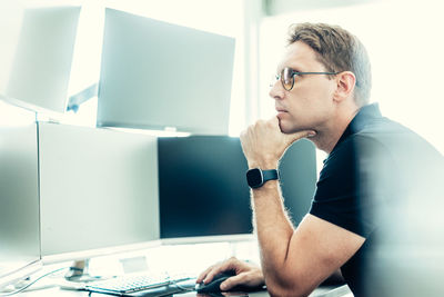 Portrait of young man using laptop at office