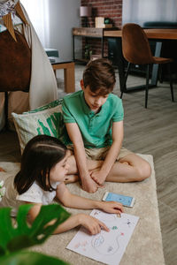 Siblings sitting on floor at home