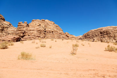 Rock formations on landscape against clear blue sky