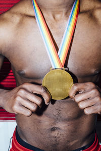 Unrecognizable shirtless african american man with fake medal standing against red wall during party