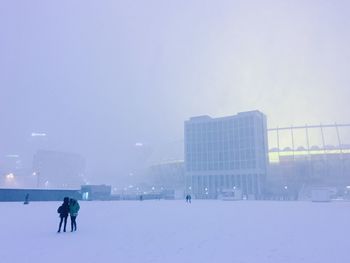 People on snow covered city against sky