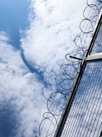 Low angle view of barbed wire fence against sky