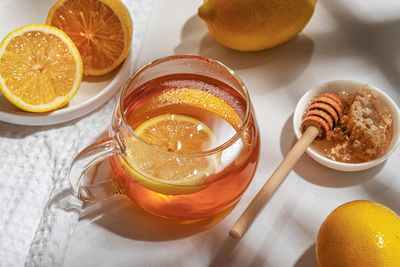 A mug of tea with lemons and a ginger root and little plate of honey on a table. top view