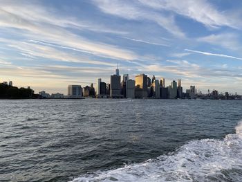 Sea by buildings in city against sky